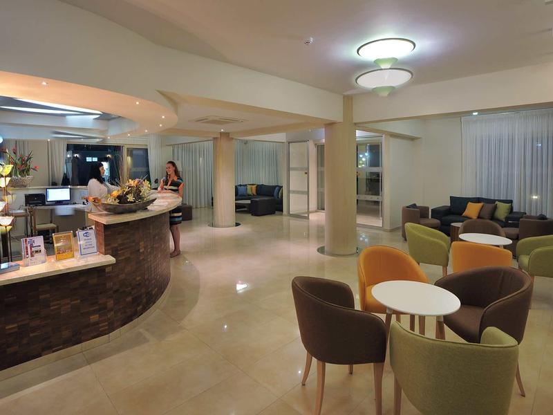 Großer moderner Empfangsbereich mit Rundtheke, Sitzgruppen und warmem LED-Licht.