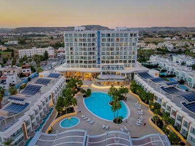 Vista de un hotel moderno con piscina y adosados contiguos al atardecer.