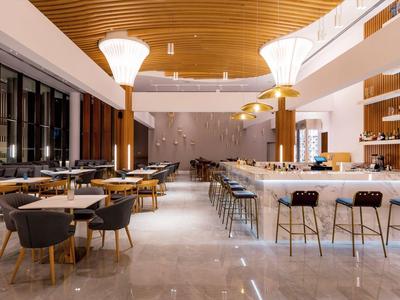 Restaurante moderno con barra redonda, sillas grises y techo de madera