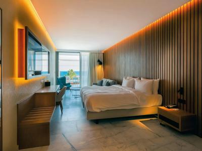 Modernes Hotelzimmer mit Doppelbett, Holzwand, indirekter Beleuchtung und Balkon mit Blick.