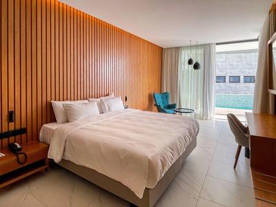 Moderndes Schlafzimmer mit Holzwand, großem Bett, Schreibtisch und Balkon mit Blick auf Pool.