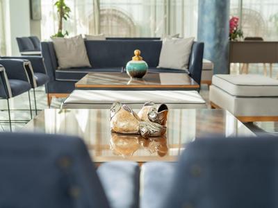 Moderní lounge s pohovkami, křesly a konferenčním stolkem s dekorací v prosvětlené místnosti.