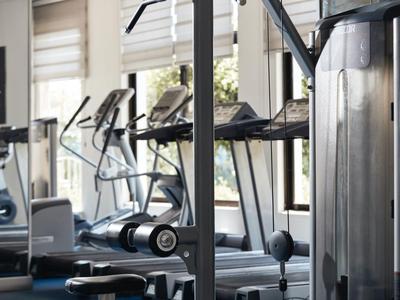 Nowoczesny sprzęt fitness w jasnej sali treningowej z dużymi oknami.