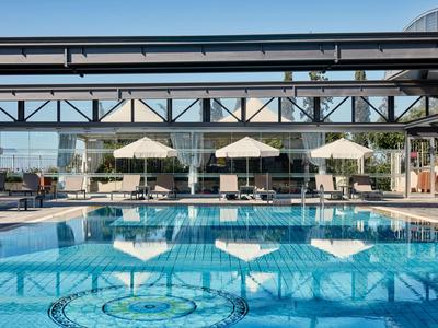 Nowoczesny basen hotelowy z leżakami i parasolami pod zadaszonym obszarem