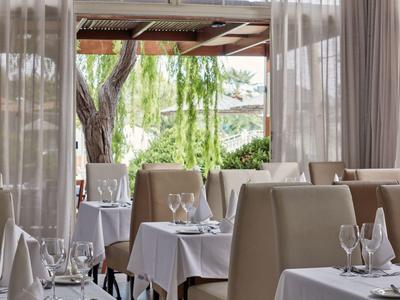 Elegant restaurant with white tablecloths and a view of a tree and lake.