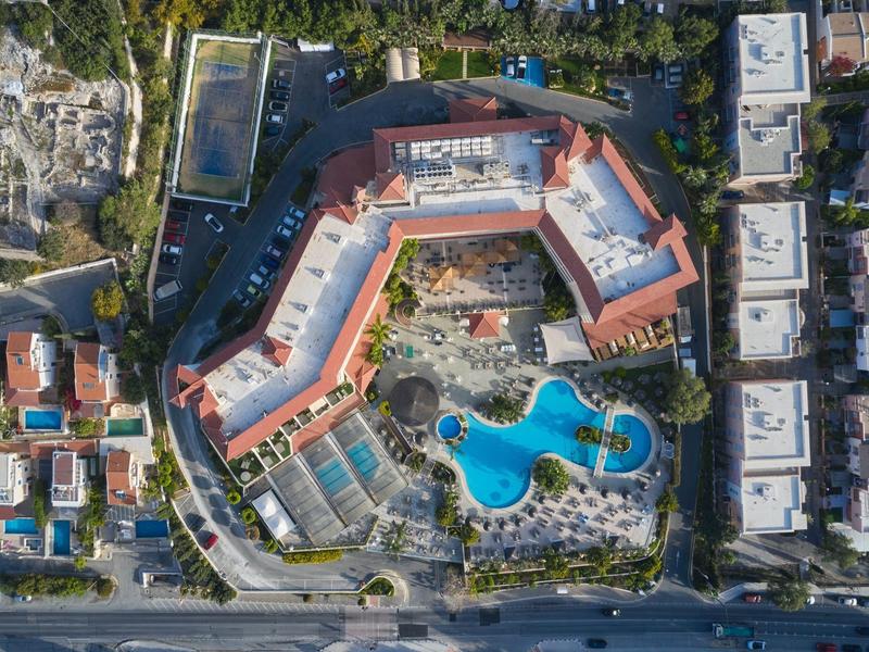 Aerial view of a hotel with swimming pool and surrounding buildings in a city.