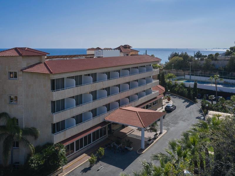 Multi-story hotel building with red roofs near the coast and sea view.