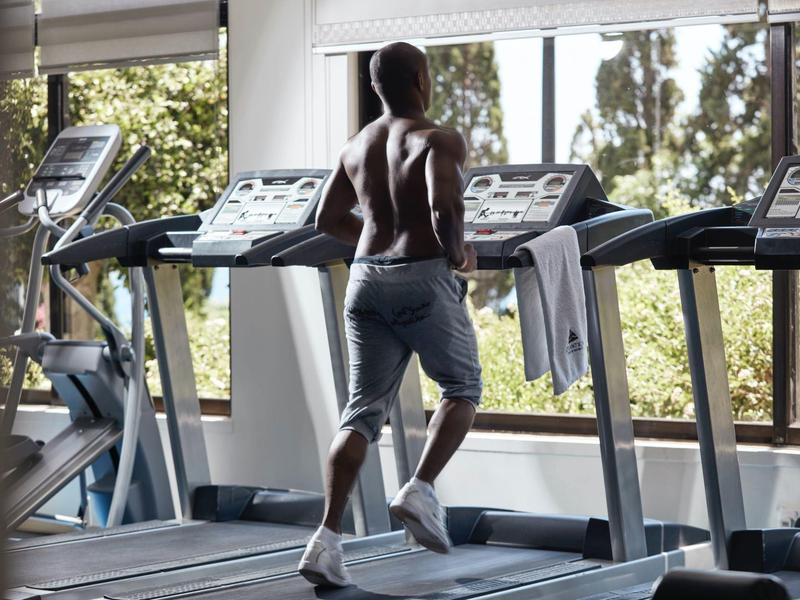 Person working out on a treadmill in a bright gym with large windows.