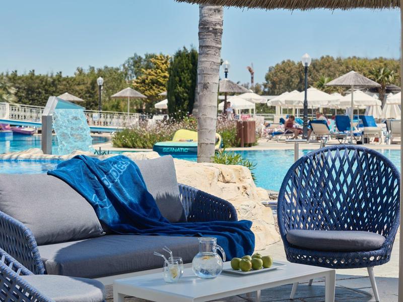 Cozy lounge furniture with blankets in a hotel pool area under sunshine.