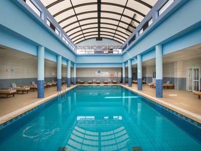 Piscina cubierta de hotel con columnas azules y gran techo de vidrio