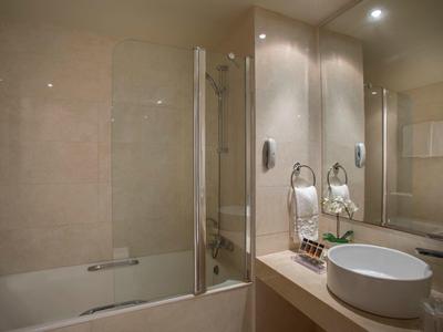 Modernes Badezimmer mit Badewanne, Duschglaswand, rundem Waschbecken und großen Spiegeln.