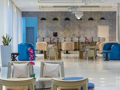 Área de salón moderna de hotel con sillones cómodos, sofás y decoración en un ambiente luminoso y acogedor.