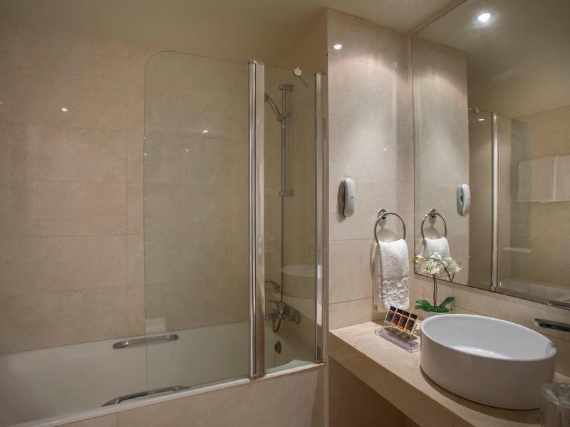 Modernes Badezimmer mit Badewanne, Duschglaswand, rundem Waschbecken und großen Spiegeln.