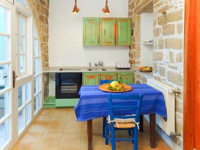 Gemütliche Küche mit blauem Tisch, grünem Schrank und Steinwand.