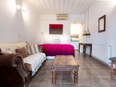 Gemütliches Wohnzimmer mit Sofa, Sessel, Holztisch und Balkon mit Blick nach draußen.