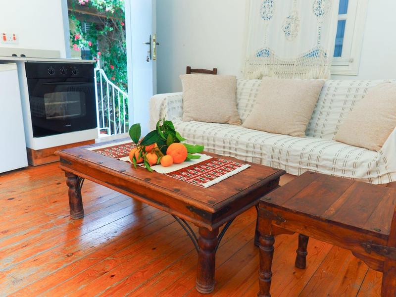 Gemütliches Wohnzimmer mit einem Holzsofa, Holztisch und einem Obstteller auf dem Tisch.
