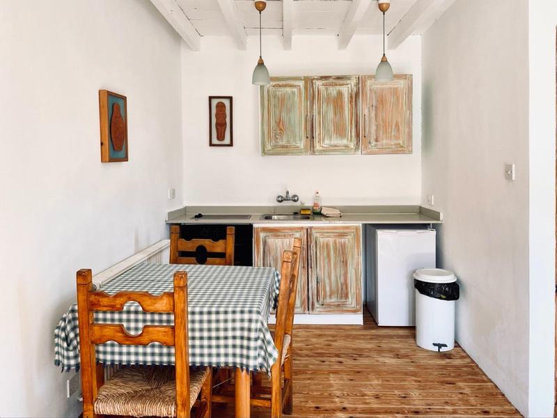 Kleine Küchenzeile mit Holztisch und kariertem Tischtuch in einem hellen Raum.