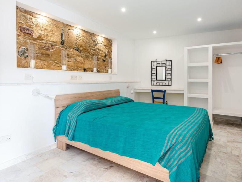 Hell eingerichtetes Hotelzimmer mit Doppelbett, blauem Bettbezug und moderner Dekoration.