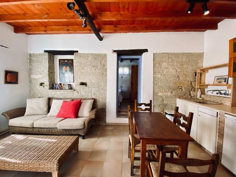 Gemütliches Zimmer mit modernem Sofa, Holztisch, Stühlen und offener Küchenzeile.