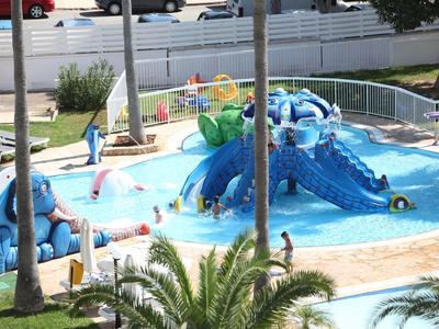 Wasserpark mit bunten Krokodilrutschen und spielenden Kindern im flachen Poolbereich.