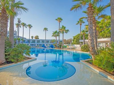 Piscina moderna dell'hotel con palme e cielo soleggiato sullo sfondo.