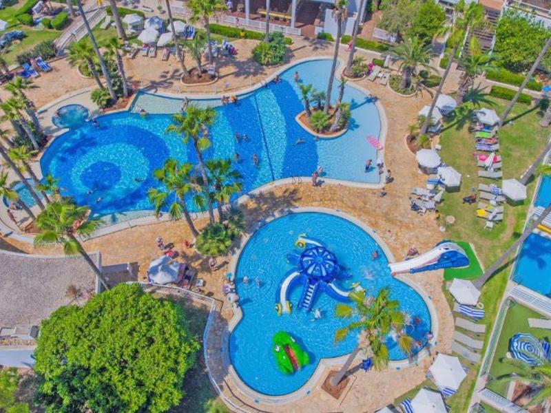 Überblick über zwei blauen Schwimmbecken mit Rutschen, Poolsitzen und Palmen in tropischer Umgebung.