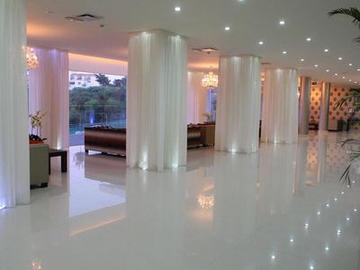 Heller, moderner Hotelflur mit weißen Säulen und reflektierendem Boden in der Dämmerung.