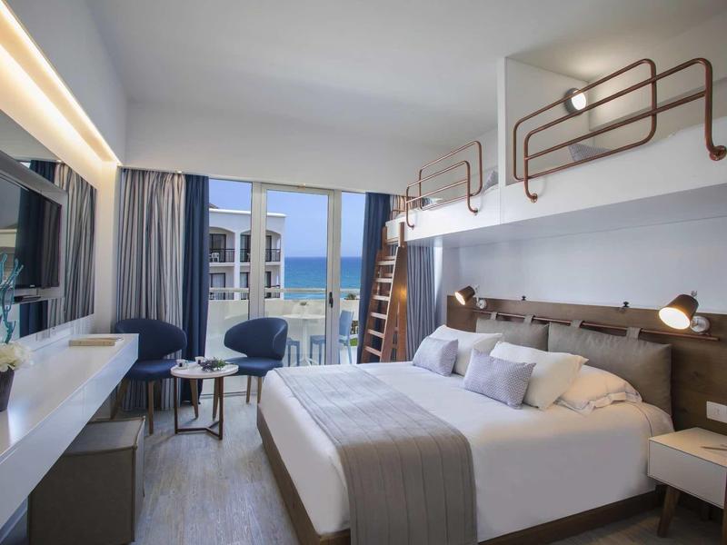 Modernes Hotelzimmer mit Doppelbett, großen Fenstern, Balkon und elegantem, hellem Interieur.