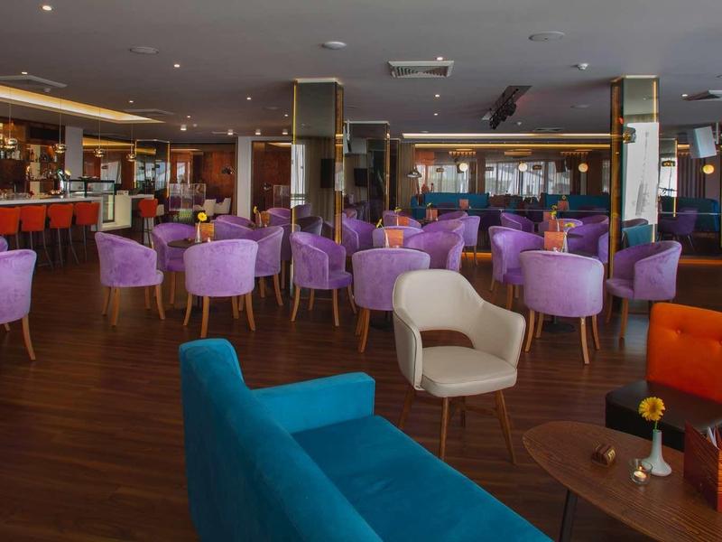 Moderner Loungebereich mit bunten Sesseln, Holzboden und gedämpfter Beleuchtung.