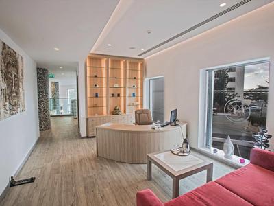 Moderní hotelová hala s kulatou recepcí, červenými pohovkami a velkými okny.