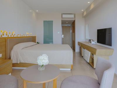 Helles Hotelzimmer mit Doppelbett, Fernsehgerät und modernem Mobiliar in neutralen Tönen.