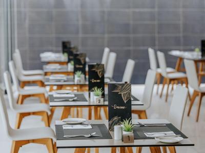 Moderner Speisesaal mit klaren Linien, weißen Stühlen und gedeckten Tischen in einem Hotel.