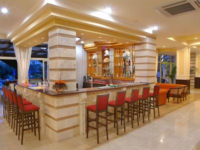 Bar di hotel moderno con lungo bancone e sgabelli rossi sotto illuminazione intensa