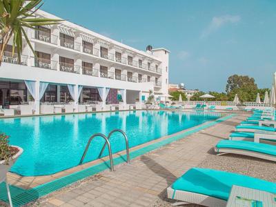 Eleganter Außenpoolbereich mit Liegestühlen vor einem Hotelgebäude an einem sonnigen Tag.