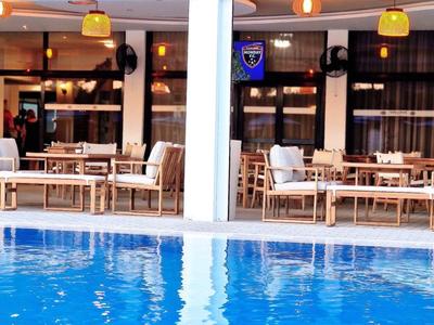 Ein moderner Außenbereich mit blauem Pool und Sitzgelegenheiten unter einem überdachten Bereich.