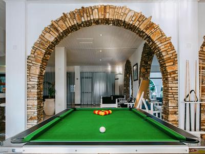 Billardtisch mit grüner Spielfläche unter einem rustikalen Bogen aus Mauersteinen in einem modernen Innenraum.