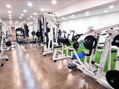 Ein moderner Fitnessraum mit verschiedenen Trainingsgeräten und Holzboden.