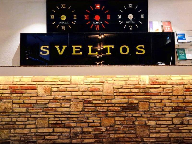 Theke mit Steinverkleidung, Leuchtschrift "SVELTOS" und mehreren kleinen Dekorationen darauf.