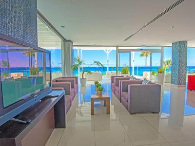 Área de lounge moderna de hotel con sofás y gran vista al mar a través de grandes ventanales