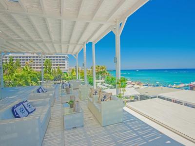 Terraza luminosa con mobiliario blanco y vista al mar con clima soleado.