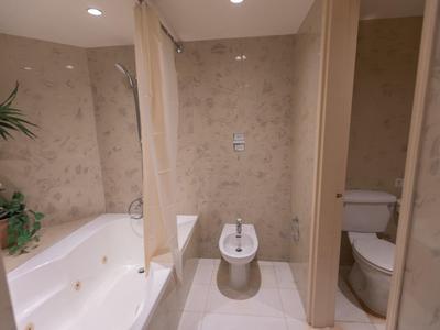 Modernes Badezimmer mit Badewanne, Bidet, WC und hellen Fliesen an Wänden und Boden.