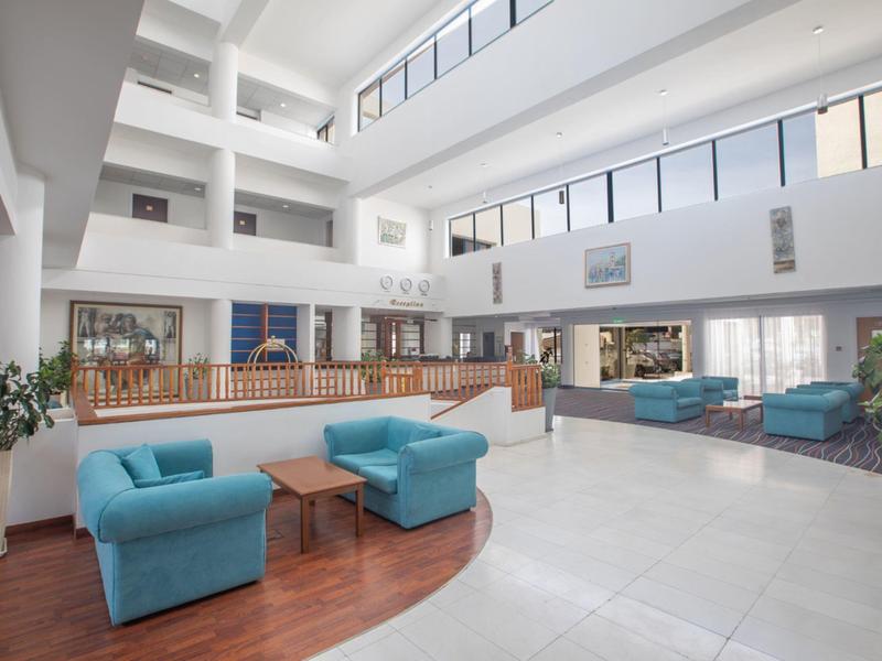 Heller, moderner Lounge-Bereich mit blauen Sesseln, Holzboden und großen Fenstern im Obergeschoss.