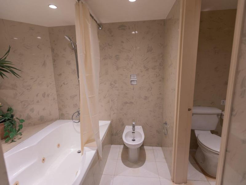 Modernes Badezimmer mit Badewanne, Bidet, WC und hellen Fliesen an Wänden und Boden.