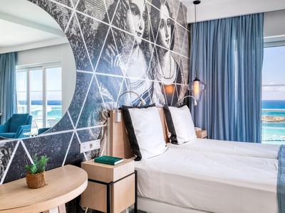 Chambre d'hôtel moderne avec deux lits, mur décoratif et vue sur la mer.