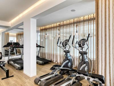 Palestra moderna con attrezzi da allenamento e grandi finestre con tende.