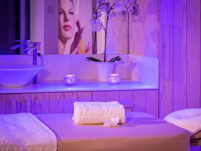 Salle de spa relaxante avec table de massage, serviettes et éclairage apaisant.