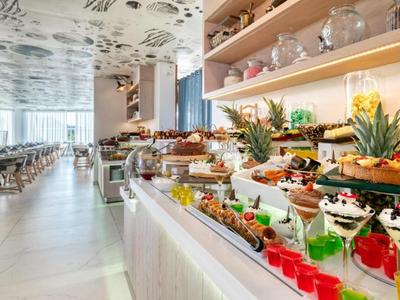 Buffet avec divers plats dans un restaurant lumineux et moderne avec plafond floral.