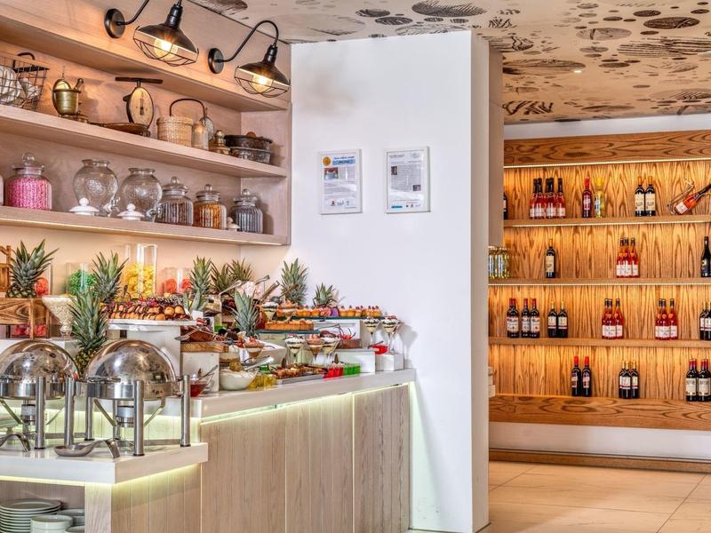 Buffet avec options petit-déjeuner, fruits frais et boissons dans un restaurant d'hôtel moderne.