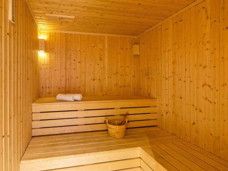 Sauna en bois clair avec bancs, seau et serviette, parfait pour la détente à l'hôtel.