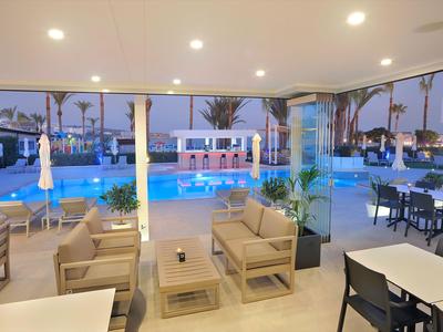 Innenbereich einer Hotel-Lounge mit Blick auf einen beleuchteten Außenpool und Sitzgelegenheiten.